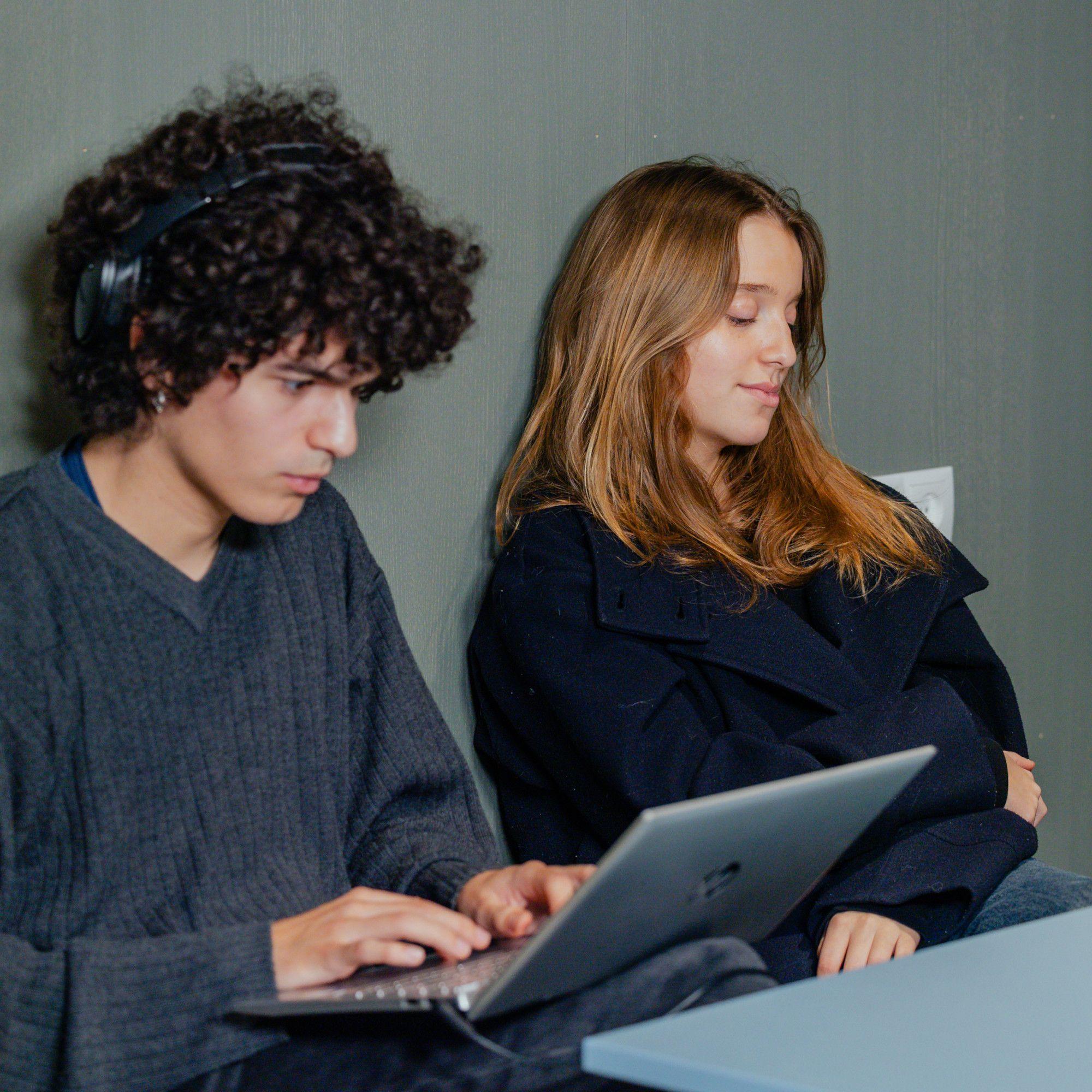 To teenagere den ene arbejdere på computeren den anden slapper af